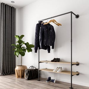 May include: A black metal clothes rack with two wooden shelves. A black leather jacket and a dark blue sweater hang on the rack. Shoes and a bag are placed on the shelves and floor. A potted plant and a curtain are in the background.