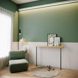 Peut inclure: Intérieur moderne avec un fauteuil vert, une console en bois avec des pieds noirs et un tapis rond. Les murs sont peints en vert et blanc, avec une lampe décorative et des œuvres d'art encadrées. La pièce est bien éclairée, créant une ambiance chaleureuse.