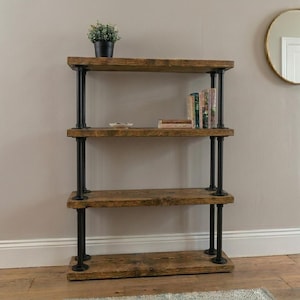 Può includere: Uno scaffale a quattro ripiani con spesse assi di legno tinto sostenute da tubi metallici neri in stile industriale. Il ripiano superiore ospita una piccola pianta in vaso, mentre il secondo contiene un piattino bianco e alcuni libri.