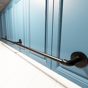 Può includere: Un corrimano in metallo nero montato su una parete azzurra. Il corrimano è costituito da un tubo dritto collegato alla parete con piastre di montaggio rotonde e nere. La parete ha un design a pannelli.