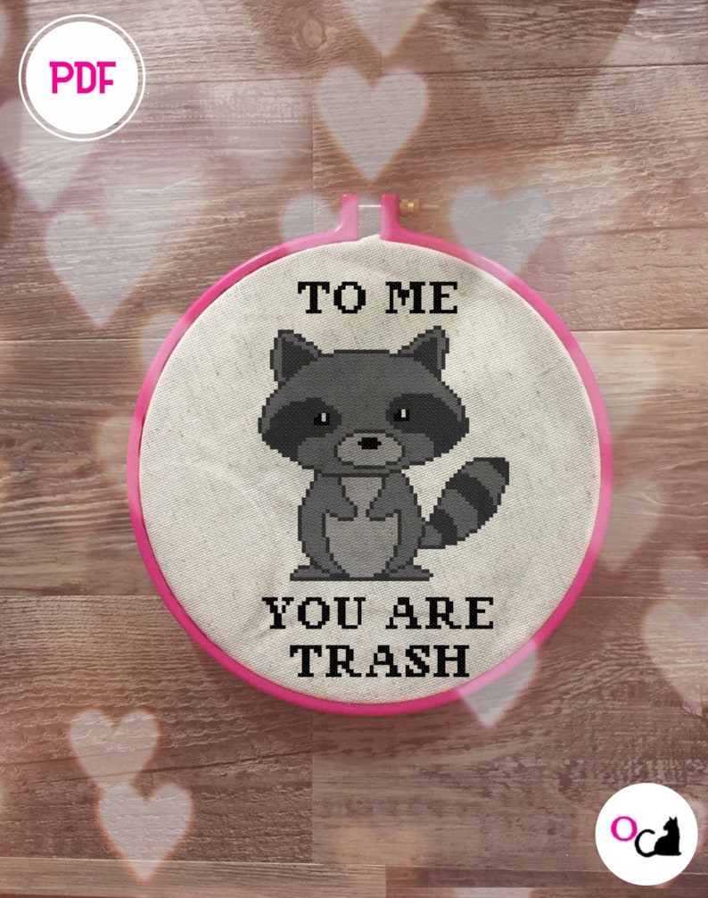 Pu&ograve; includere: Un cerchio da ricamo rosa con uno sfondo in tessuto bianco. Il tessuto presenta un'immagine pixelata in bianco e nero di un procione con il testo "To Me You Are Trash".