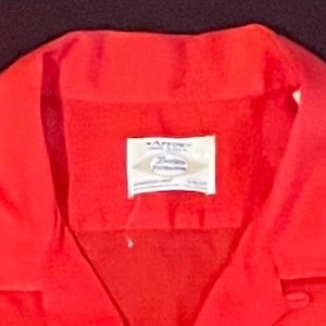 Puede incluir: Una camisa roja con cuello y una etiqueta blanca que dice "Arrow Premium Fashion"