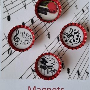 May include: Four red bottle cap magnets with different musical designs. The designs include a piano with musical notes, a treble clef with musical notes, a musical note with stars, and a piano keyboard with a red rose.