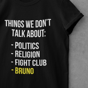 May include: Black t-shirt with white text that reads "THINGS WE DON'T TALK ABOUT: - POLITICS - RELIGION - FIGHT CLUB - BRUNO".