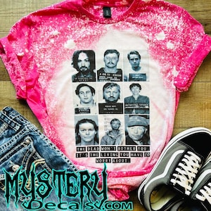 May include: Pink bleached t-shirt with a graphic of mugshots of people with the text "The dead won't bother you, it's the living you have to worry about."