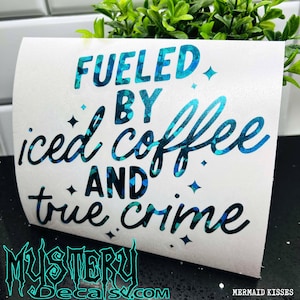 May include: A white vinyl decal with blue glitter lettering that reads "Fueled by iced coffee and true crime".
