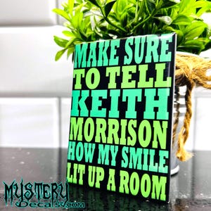 May include: A black and green magnet with the text "MAKE SURE TO TELL KEITH MORRISON HOW MY SMILE LIT UP A ROOM".