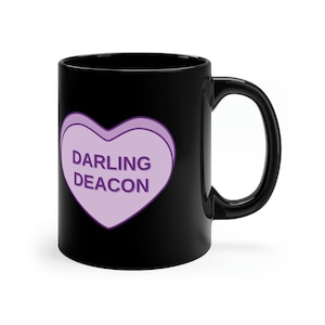 Puede incluir: Taza de cerámica negra con un diseño en forma de corazón morado que dice "Darling Deacon".