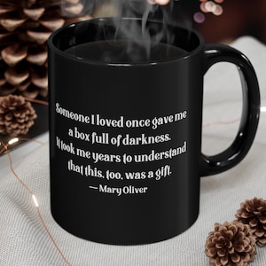 May include: Black coffee mug with white text that reads "Someone I loved once gave me a box full of darkness. It took me years to understand that this, too, was a gift. - Mary Oliver"