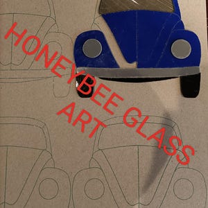 May include: A blue glass car with silver accents and black tires. The car is a cutout design, with a light brown background. The words "HONEYBEE GLASS ART" are written in red diagonally across the image.