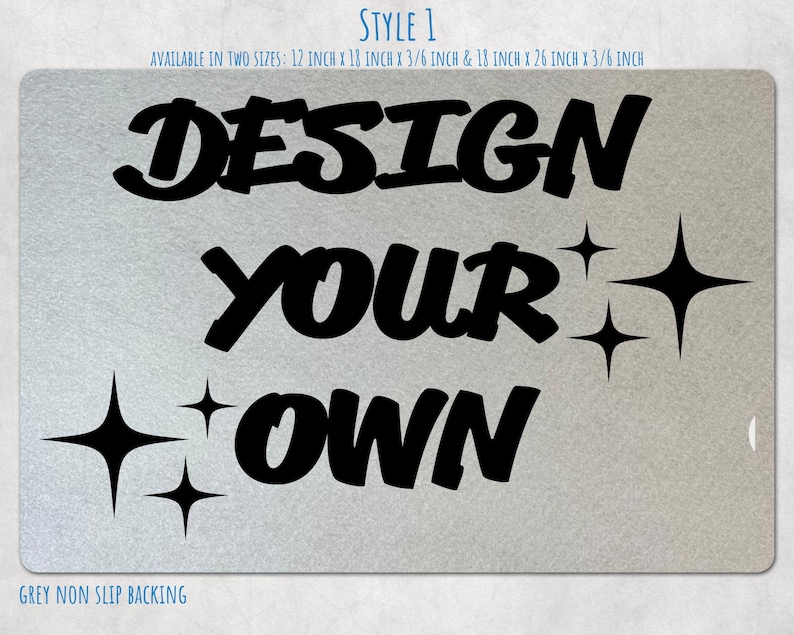 May include: A rectangular mat with a light grey textured surface featuring the black text "DESIGN YOUR OWN" and four black four-pointed star icons. Text above indicates two sizes: 12 inch x 18 inch x 3/8 inch and 18 inch x 26 inch x 3/8 inch.