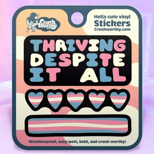 May include: A sticker sheet with the text "THRIVING DESPITE IT ALL" in a black rectangle. Below are five heart stickers and a horizontal stripe, all in the colors of the transgender pride flag. The sheet also includes the text "Hella cute vinyl Stickers Crushworthy.com".