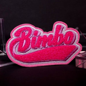 May include: Pink felt patch with the word "Bimbo" in white outlined letters. The patch is on a black background.