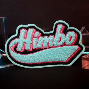 May include: A blue and pink embroidered patch with the word "Himbo" in a retro font style.