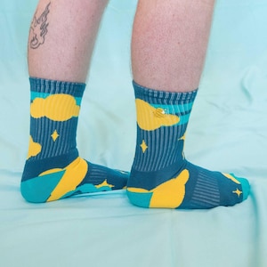 May include: A pair of blue socks with a yellow cloud and star pattern. The socks are made of a soft, comfortable material and are perfect for everyday wear.