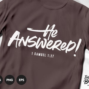 May include: A brown t-shirt with white text that reads "He Answered! 1 Samuel 1:27". The text is in a bold, brush-stroke font. The t-shirt is a blank template for a design.
