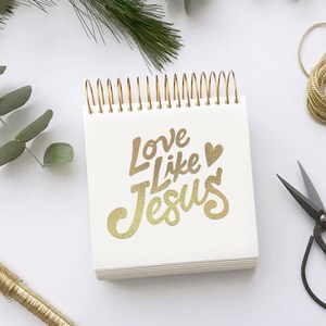 May include: A white spiral bound notebook with gold lettering that says "Love Like Jesus" with a small gold heart.