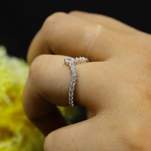 May include: A silver ring with a V-shaped design set with small, clear stones.