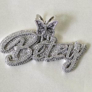 May include: A silver pendant with the name "Betsy" spelled out in sparkling cubic zirconia stones. A small butterfly charm with cubic zirconia stones is attached to the top of the pendant.