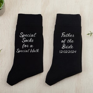 Könnte beinhalten: Ein Paar schwarze Socken mit weißem Text. Eine Socke sagt "Special Socks for a Special Walk". Die andere Socke sagt "Father of the Bride 12/02/2024".