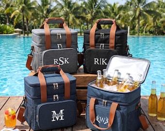 Könnte beinhalten: Vier isolierte Kühltaschen in Grau, Schwarz und Marineblau mit braunen Griffen und Riemen. Jede Tasche hat eine Vordertasche mit weißem personalisiertem Text oder Monogrammen wie RSK, R|K, MICHAEL und W. Eine Tasche ist offen und zeigt Glasflaschen.