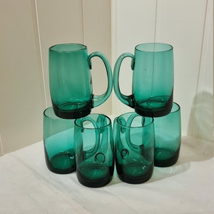 May include: Set of six teal green glass mugs, two with handles and four without. The mugs are stacked in a pyramid shape.