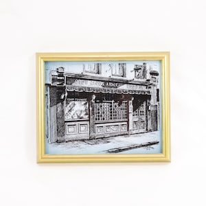 Puede incluir: Una ilustración en blanco y negro de un pub llamado "The New King's Arms" con las palabras "John Courage" impresas debajo del nombre del pub.