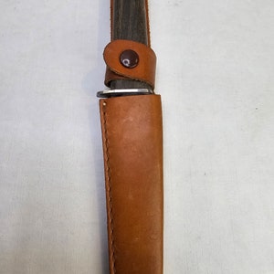 May include: A brown leather sheath with a brown wooden handle knife inside.