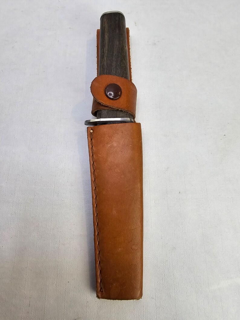 May include: A brown leather sheath with a brown wooden handle knife inside.