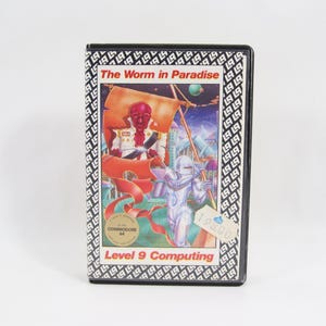 Könnte beinhalten: Eine Vintage-Spielkassette für den Commodore 64 mit dem Titel "The Worm in Paradise" von Level 9 Computing. Das Cover zeigt eine futuristische Szene mit einer rot-häutigen Figur und einem Roboter. Die Kassette hat einen schwarz-weißen Musterrahmen.
