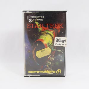 May include: A retro Commodore 64 game cartridge for Star Trek, with a vibrant spaceship illustration on the cover. The game case has a sticker from Kings. The Interceptor Software logo is visible.