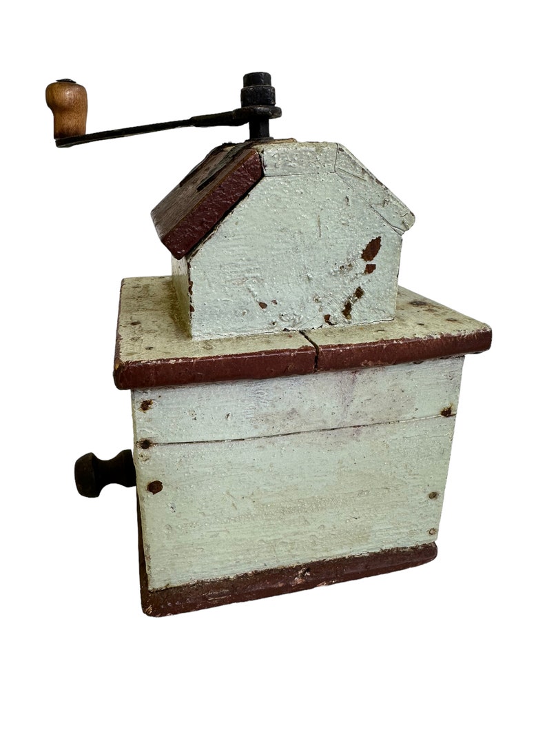 May include: A vintage wooden coffee grinder with a hand crank. The grinder is painted white with brown accents and has a small wooden handle.
