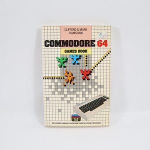 Könnte beinhalten: Ein Vintage Commodore 64 Spielebuch mit pixeligem Design. Auf dem Cover steht "COMMODORE 64 GAMES BOOK" und eine Tastatur-Illustration. Das Buch ist ein Retro-Gaming-Sammlerstück.