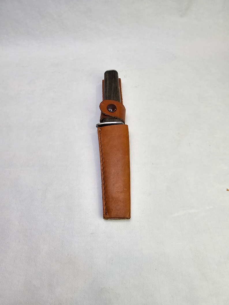 May include: A brown leather sheath with a snap closure, holding a black handled knife.