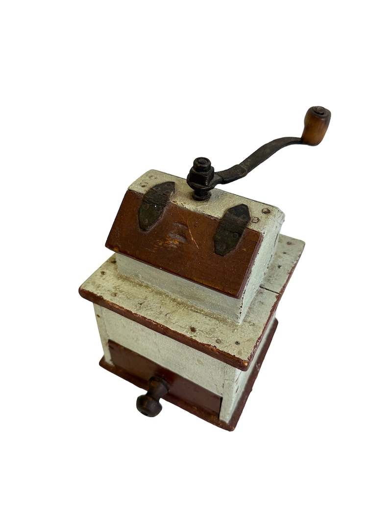 May include: A vintage wooden coffee grinder with a hand crank and a drawer. The grinder is painted white with brown accents and has metal accents.