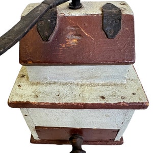 May include: Antique wooden coffee grinder with a hand crank and a brown and white painted finish.
