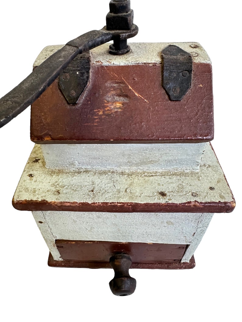 May include: Antique wooden coffee grinder with a hand crank and a brown and white painted finish.