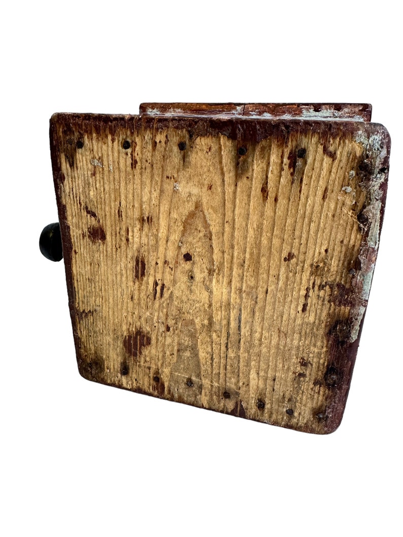 May include: A wooden box with a hinged lid and a small handle. The box is made of rough-hewn wood and has a rustic appearance. The box is painted a dark brown color and has a few nails visible.