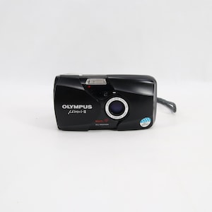 May include: A black Olympus mju-II point-and-shoot film camera featuring a sliding lens cover, a central lens with Olympus Lens 35mm 1:2.8 text, a built-in flash, and a small wrist strap attached to the side of the compact, rounded rectangular body.