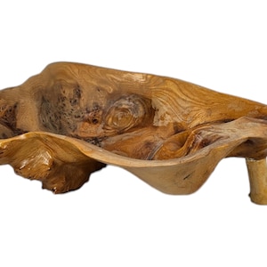 May include: A large, wooden bowl with a unique, organic shape. The bowl is made from a single piece of wood and has a natural, rustic finish. It has a single leg on one side.