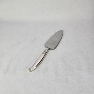 May include: A silver cake server with a decorative handle. The handle has a floral design.