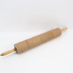 May include: A wooden rolling pin with a grooved, cylindrical barrel and two tapered handles. The barrel has a series of parallel, dark brown grooves. The handles are a lighter shade of wood. The rolling pin is designed for baking.