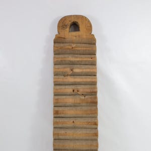 May include: A vintage wooden washboard with a rounded top handle and a series of raised ridges for scrubbing clothes.