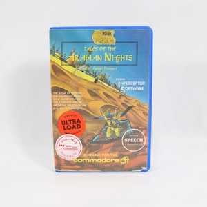 Puede incluir: Un cartucho de juego vintage de Commodore 64 titulado "Tales of the Arabian Nights". La caja presenta una escena desértica con figuras y texto. Incluye el texto "ULTRA LOAD" y "SPEECH". La caja es azul con una etiqueta de precio amarilla.