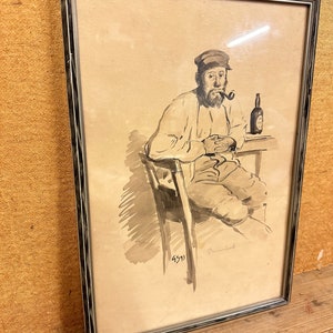 May include: A framed black and white ink drawing of a man sitting in a chair with a pipe in his mouth and a bottle of beer on a table. The drawing is signed "Dementi" and dated "4511".