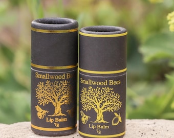 May include: Two black tubes of lip balm with gold lettering and a gold tree design. The tubes are labelled "Smallwood Bees Lip Balm 7g".