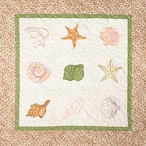 May include: A white background with a green border, featuring nine embroidered images of seashells and starfish. The images are in a grid pattern, with three rows and three columns.