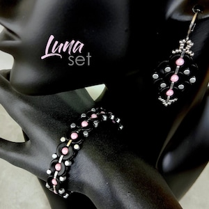 Peut inclure: Un ensemble de bracelet et boucles d'oreilles noir et argent avec des perles roses. L'ensemble s'appelle "Luna set".