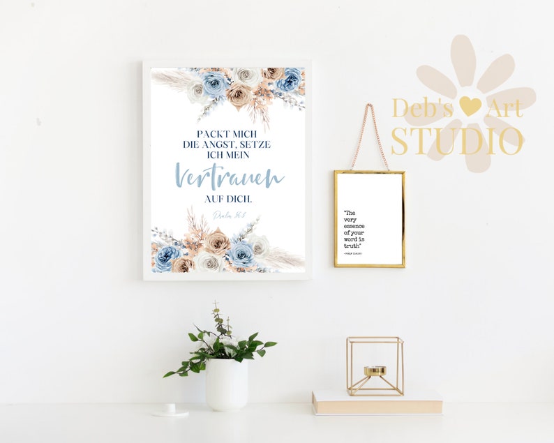 Pode incluir: Uma impress&atilde;o emoldurada branca com um design floral e o texto "PACKT MICH DIE ANGST, SETZE ICH MEIN VERTRAUEN AUF DICH.  PSALM 56:3" em letras azuis e marrons. A impress&atilde;o est&aacute; pendurada em uma parede branca com uma impress&atilde;o emoldurada branca menor pendurada abaixo. A impress&atilde;o menor tem o texto "The very essence of your word is truth." em letras pretas.