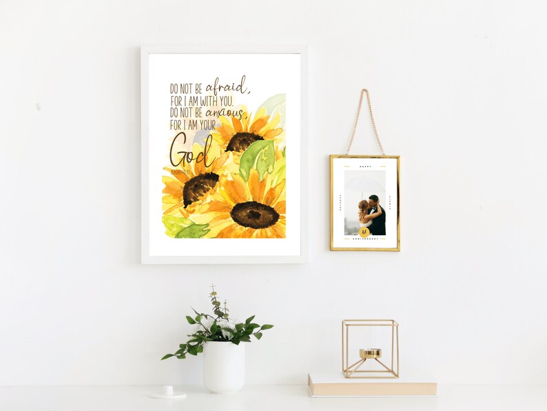 Op de afbeelding: Een wit ingelijst afdruk met een aquarel van zonnebloemen en de tekst "DO NOT BE afraid, FOR I AM WITH YOU. DO NOT BE anxious FOR I AM YOUR God."